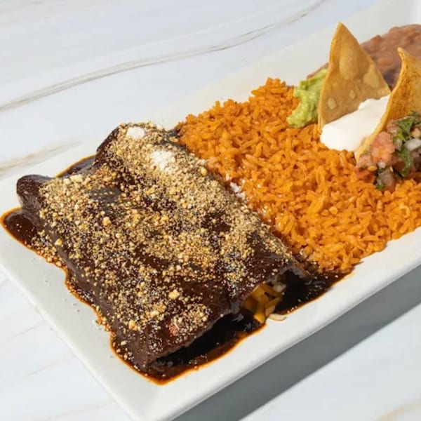 Friducha's enchiladas with rich mole sauce, rice, refried beans, guacamole, and tortilla chips.